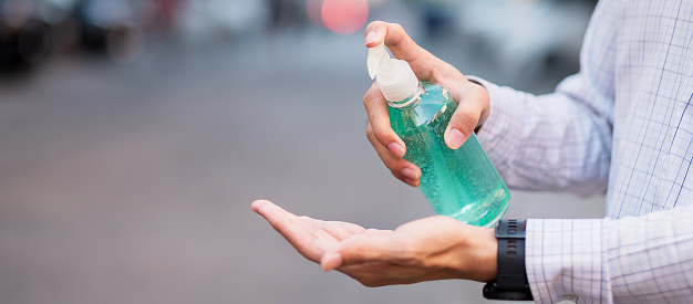 man hand using wash hand sanitizer gel dispenser, against Novel coronavirus or Corona Virus Disease (Covid-19) at public outdoor. Antiseptic, Hygiene and Healthcare concept