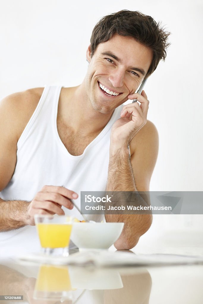 Smiling young guy talking on cellphone while having breakfast  20-24 Years Stock Photo