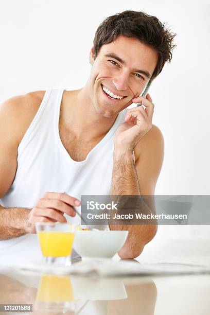 Smiling Young Guy Talking On Cellphone While Having Breakfast Stock Photo - Download Image Now