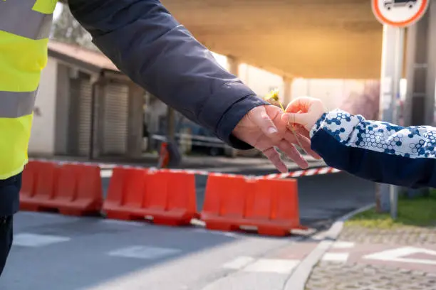 Photo of Closure of the state border crossing; a child hand close up giving flower to a border safety guard