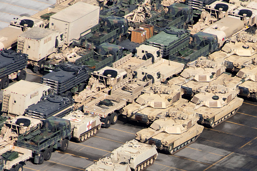 Large group of army vehicles and aircraft in a military base.