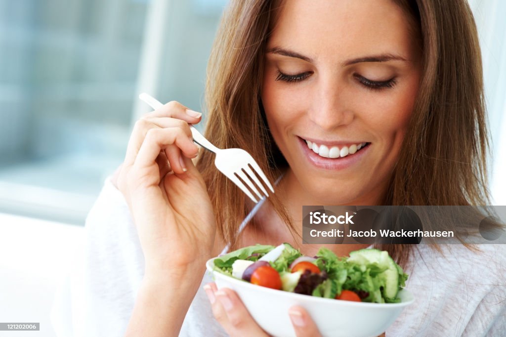 Close-up de uma jovem mulher feliz comendo salada - Foto de stock de Comer royalty-free