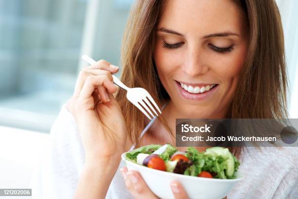 Foto de Closeup De Uma Jovem Mulher Feliz Comendo Salada e mais fotos de stock de Comer - Comer, Face Humana, Garfo