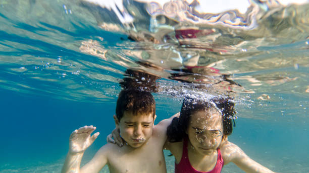 istock Two kids with closed eyes diving into the sea 1212021603