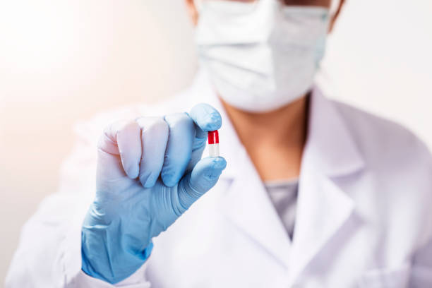 istock Young attractive female scientist holding a red transparent pill 1212021634