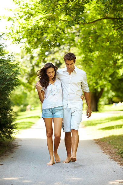 istock Romantic young couple walking on path in park 121202223