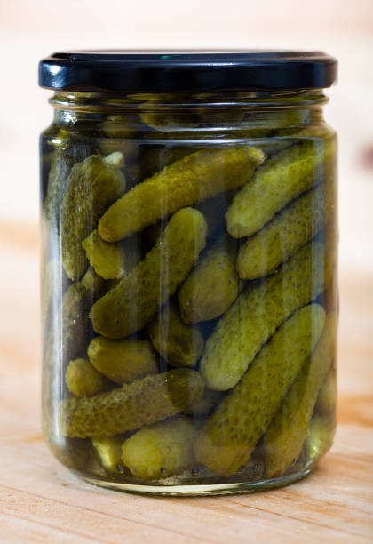 istock Pickled cucumbers with spices in glass jar on a wooden surface 1212024466