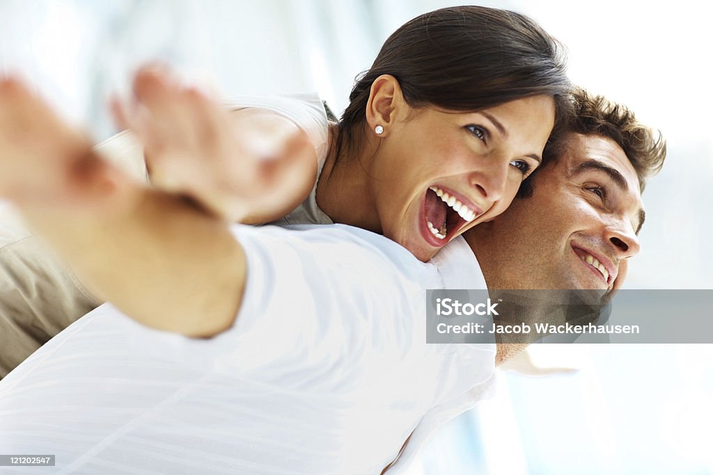 Playful young couple having fun PLayful young female carrying his girlfriend on back with their hands outstretched 20-24 Years Stock Photo