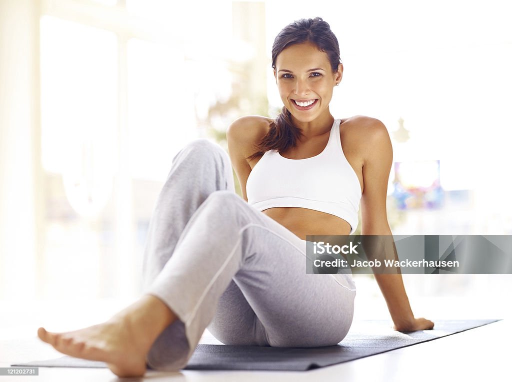 Giovane donna a riposo dopo l'esercizio sul tappetino fitness - Foto stock royalty-free di Donne