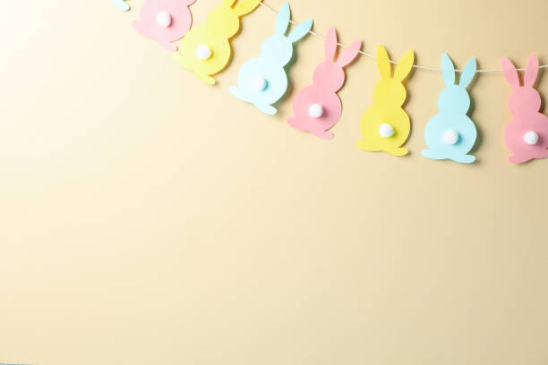 istock Twine with colorful bunnies on beige background, space for text 1212027324