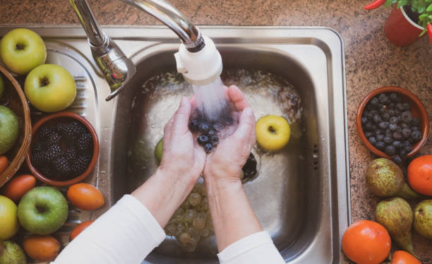 A woman's hands wash some fruit under the stream of water. Background with an assortment of healthy freshly picked fresh fruit. Eat healthy. One person A woman's hands wash some fruit under the stream of water. Background with an assortment of healthy freshly picked fresh fruit. Eat healthy. One person pomegranate in spanish stock pictures, royalty-free photos & images