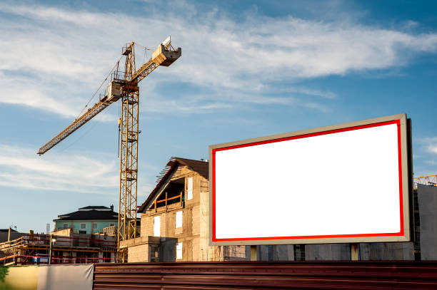 istock Blank billboard for advertisement on the construction site with cranes on a sunny day. 1212029522