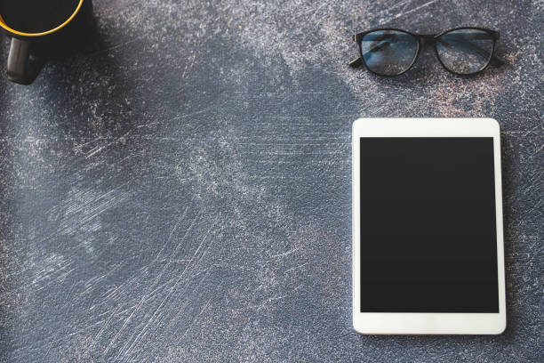 istock Eyeglasses, digital tablet and coffee on office desk 1212029647