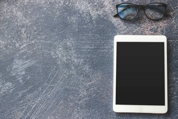 istock Eyeglasses and digital tablet on dark background 1212029760