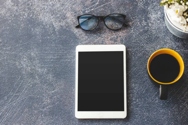 istock Eyeglasses, digital tablet and coffee on office desk 1212029963