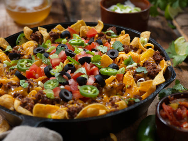 Baked Frito Pie (Chili Corn Chip Nachos) with Black Olives, Tomatoes, Green Onions, Jalapenos, Salsa, Guacamole and Sour Cream Baked Frito Pie (Chili Corn Chip Nachos) with Black Olives, Tomatoes, Green Onions, Jalapenos, Salsa, Guacamole and Sour Cream nacho chip photos stock pictures, royalty-free photos & images