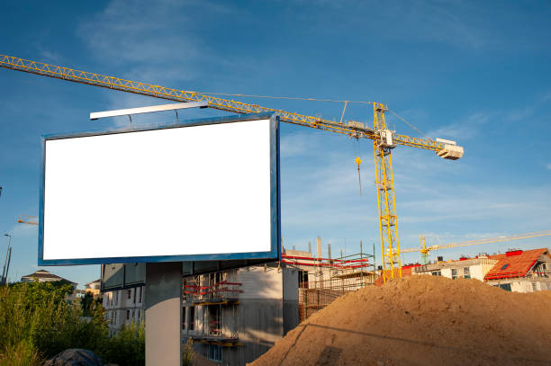 istock Blank billboard for advertisement on the construction site with cranes on a sunny day. 1212030094