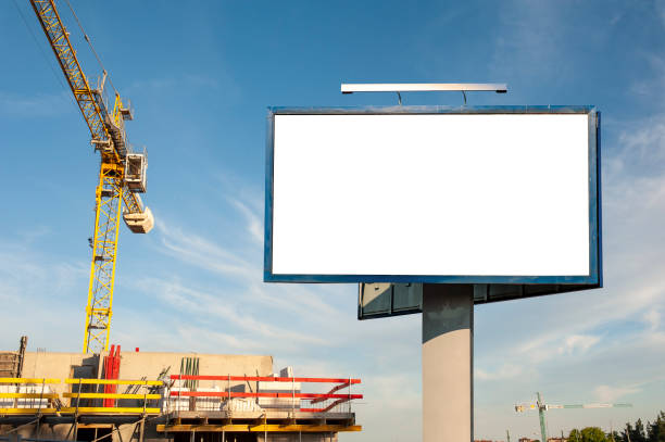 istock Blank billboard for advertisement on the construction site with cranes on a sunny day. 1212030627