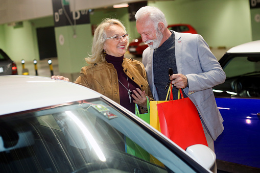 Senior couple in a shopping mall garage. Both about 65 years old, Caucasian people.