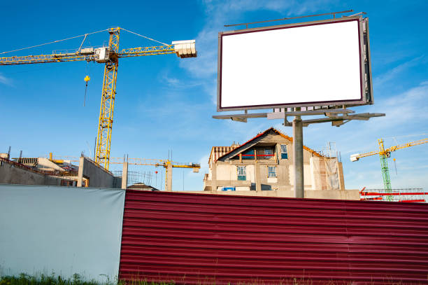 istock Blank billboard for advertisement on the construction site with cranes on a sunny day. 1212030881