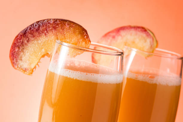 Bellini champagne cocktail in crystal glass on orange background