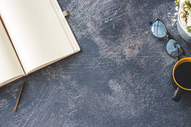 Notebook, coffee cup and eyeglasses on modern office desk