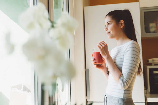 istock Woman enjoying her smoothie, looking out the window 1212033892