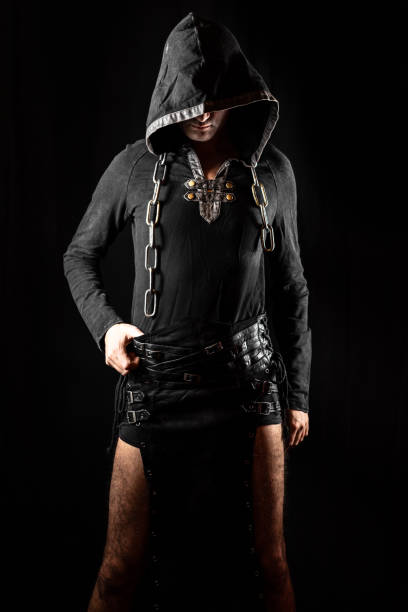istock Young man posing in hooded gothic clothes with chain around neck 1212033896