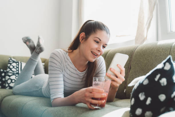 istock Woman holding a smoothie lying on the sofa 1212034173