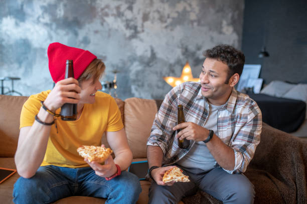 istock Two young men sitting on the sofa and drinking beer 1212034641