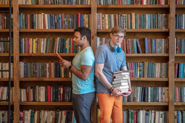 istock Two young men standing in the library back to back 1212035694