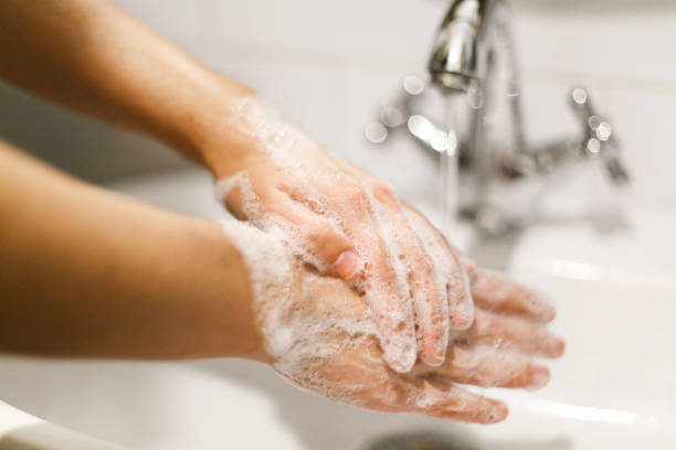 lavarsi le mani. lavaggio delle mani con schiuma di sapone sullo sfondo dell'acqua che scorre dal rubinetto. prevenzione delle malattie influenzale. igiene personale. come pulire le mani a destra - lavarsi le mani foto e immagini stock