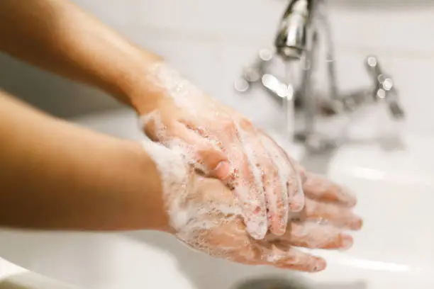 Washing hands. Hands washing with soap foam on background of water flowing from faucet. Prevention of flu disease. Personal hygiene. How to clean hands right