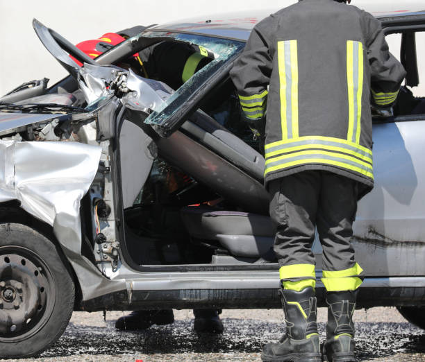 istock firefighter with uniofmr and helmet and a broken car 1212036823