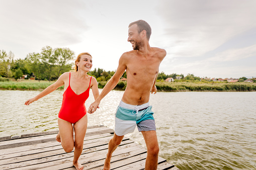 Photo of a young couple jumping together into the lake