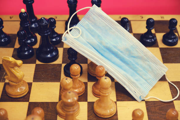 istock Medical mask on a chessboard with pieces, quarantine closeup 1212039901