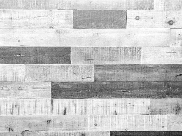 A full frame monochrome gray, black and white wood grain boards background made with old rough textured knotted wood timber.