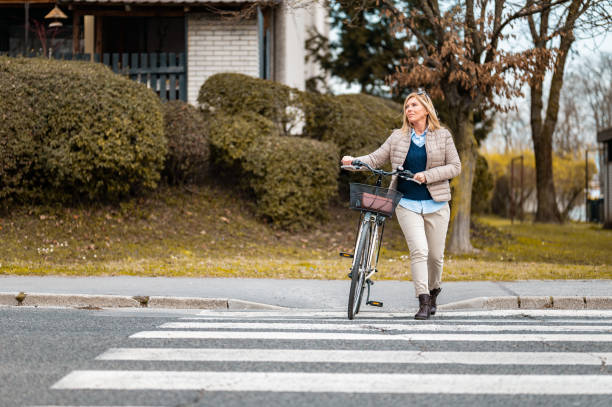 istock Woman crossing a street with a bicycle 1212042021