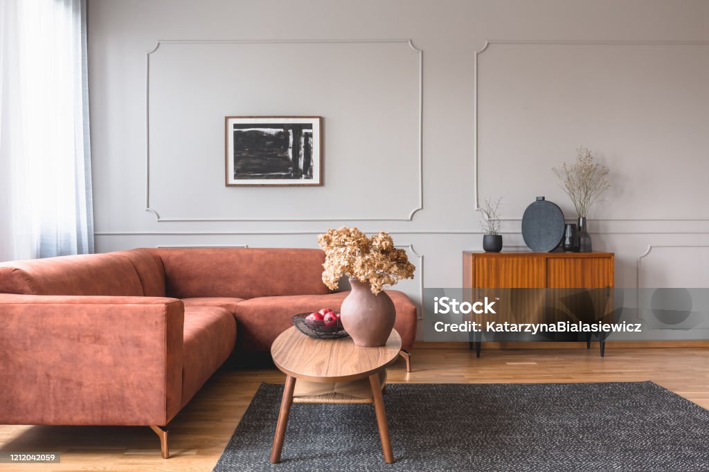 Retro wooden cabinet with black vases in the corner of classy grey living room interior with ginger sofa Molding a Shape Stock Photo