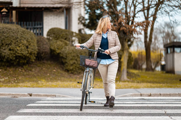 istock Woman crossing a street with a bicycle 1212042064