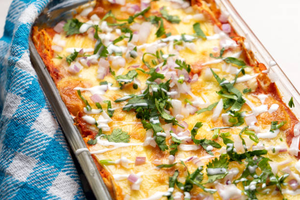 istock Mexican red baked enchiladas with melted cheese and sour cream on white background 1212043394