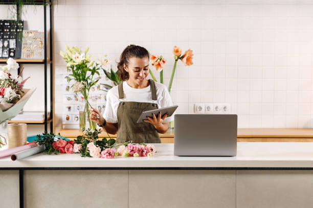 Florist using digital tablet in flower shop. Woman making a bouquet at the counter. Florist using digital tablet in flower shop. Woman making a bouquet at the counter. retail occupation photos stock pictures, royalty-free photos & images