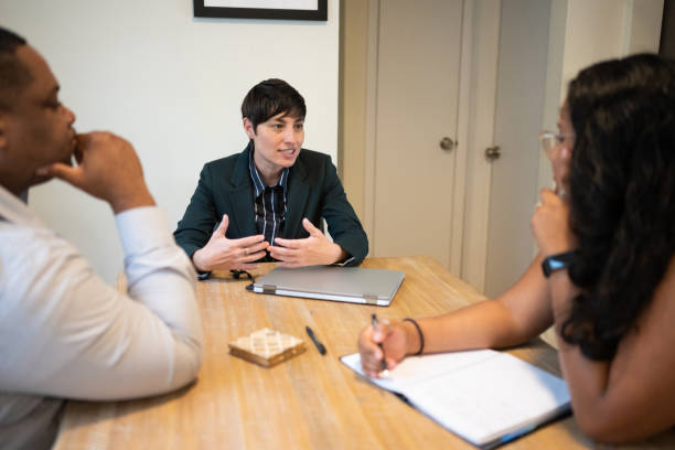 Gender Neutral Person Leads Community Outreach Meeting for Multi Ethnic Group of Non Profit Professionals This is a photograph of a confident Caucasian gender non conforming person with short hair leading a meeting for a small multi ethnic group of non-profit professionals. gender neutral photos stock pictures, royalty-free photos & images