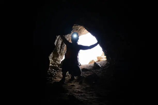 Historic World-War I tunnel and a woman tourist with a head torch on, at via ferrata Delle Trincee galleries (meaning Way of the trenches), in Dolomites mountains, Italy.