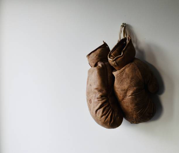 old champions Pair of old and worn boxing gloves hang on the wall weight class stock pictures, royalty-free photos & images