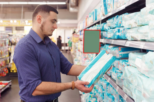 man with diaper pack in supermarket reading product information man with diaper pack in supermarket reading product information. adult diaper stock pictures, royalty-free photos & images