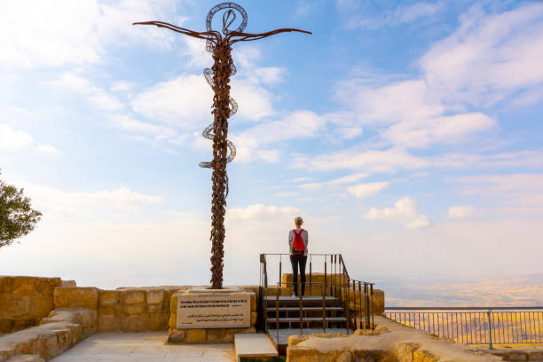 Womans standing next to The Brazen Serpent by Italian artist Giovanni Fantoni) on top of Mount Nebo, overlooking the holy land Mount Nebo, Jordan, March 2020: Womans standing next to The Brazen Serpent by Italian artist Giovanni Fantoni) on top of Mount Nebo, overlooking the holy land mount nebo jordan stock pictures, royalty-free photos & images