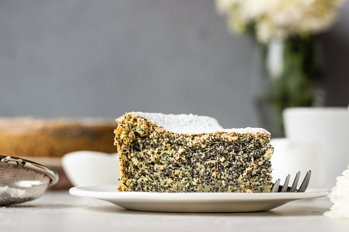 Poppy seed cake with powdered sugar and custard with a cup of coffee. Traditional Polish poppy seed cake – Makovnik. Delicious breakfast or dessert.