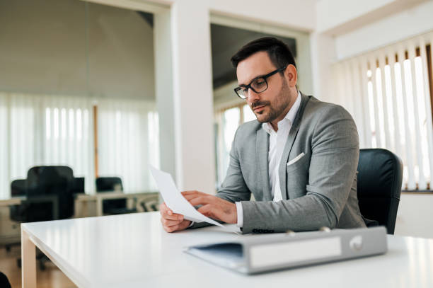 istock Serious business executive reading report, looking at paper document. 1212062374