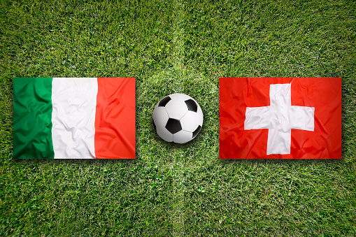 Italy vs. Switzerland flags on green soccer field